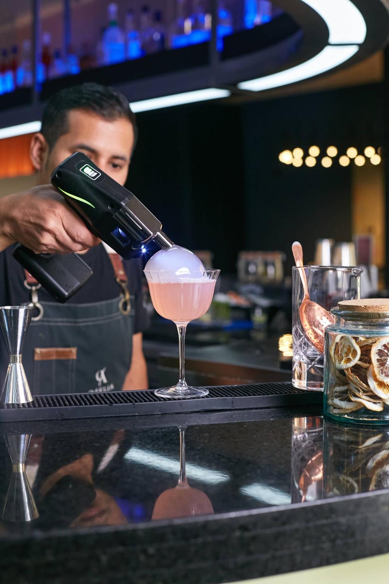 Pullman Santiago Vitacura ภายนอก รูปภาพ A bartender using a blowtorch to cook a cocktail